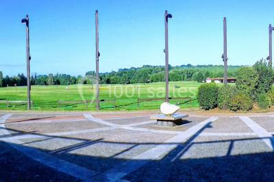 Salle de réception décorée avec des tables rondes, nappes blanches et chaises ornées de nœuds colorés.