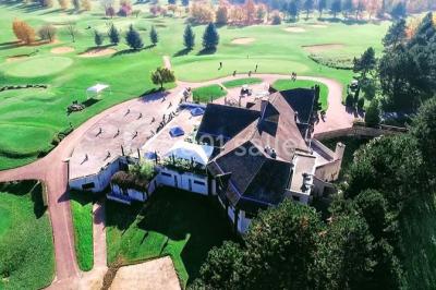 Salle de réception décorée avec des tables rondes, nappes blanches et chaises ornées de nœuds colorés.