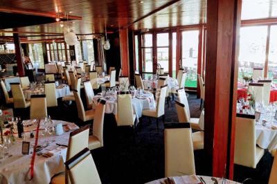 Salle de réception décorée avec des tables rondes, nappes blanches et chaises ornées de nœuds colorés.