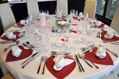 Salle de réception décorée avec des tables rondes, nappes blanches et chaises ornées de nœuds colorés.