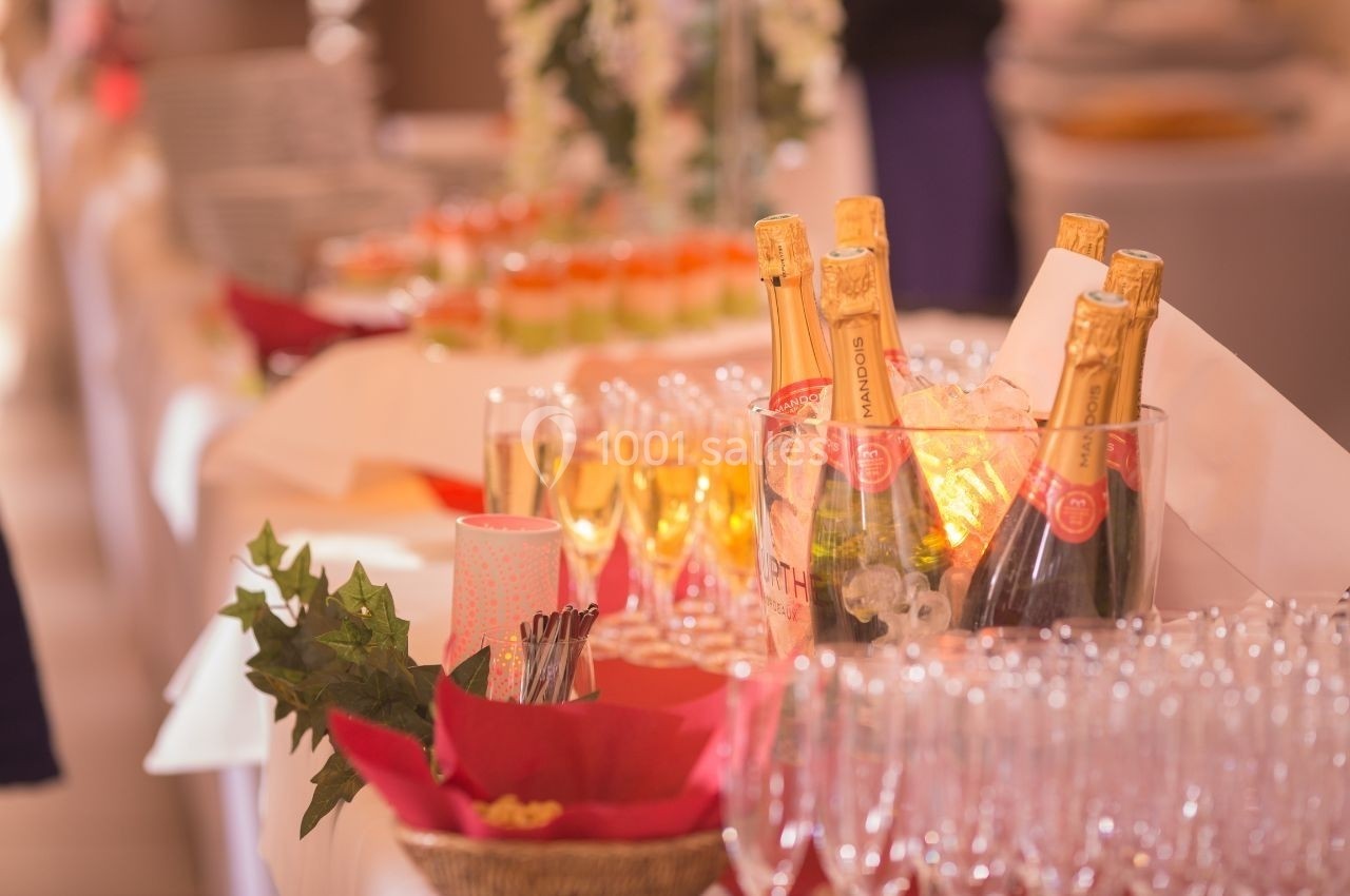 Bouteilles de champagne et verres disposés sur une table avec des décorations et des amuse-bouches en arrière-plan.