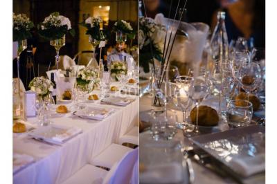 Salle en pierre avec arches, tables décorées et stands alignés, éclairage chaleureux créant une ambiance conviviale.