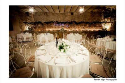 Salle en pierre avec arches, tables décorées et stands alignés, éclairage chaleureux créant une ambiance conviviale.