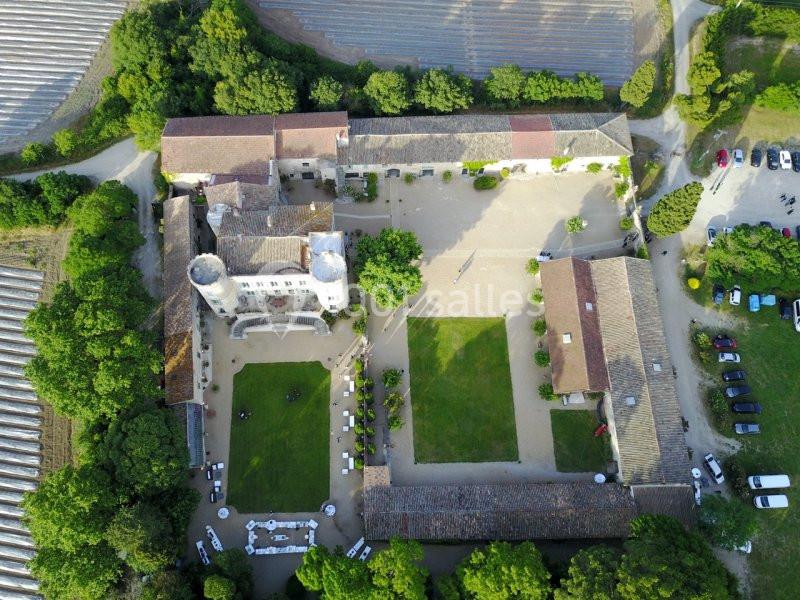 Vue aérienne d'un domaine avec bâtiments anciens, cour centrale, espaces verts et parkings entourés de végétation.