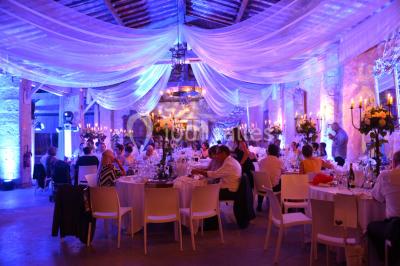 Salle en pierre avec arches, tables décorées et stands alignés, éclairage chaleureux créant une ambiance conviviale.