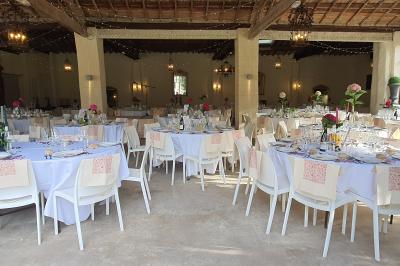 Salle en pierre avec arches, tables décorées et stands alignés, éclairage chaleureux créant une ambiance conviviale.