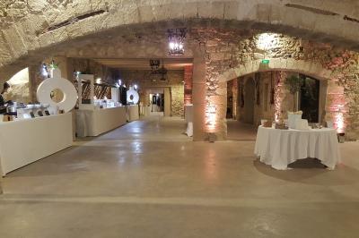 Salle en pierre avec arches, tables décorées et stands alignés, éclairage chaleureux créant une ambiance conviviale.