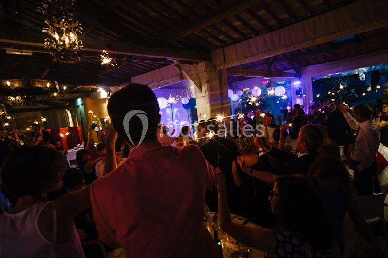 Des invités célèbrent dans une salle décorée, tenant des cierges magiques allumés dans une ambiance festive.