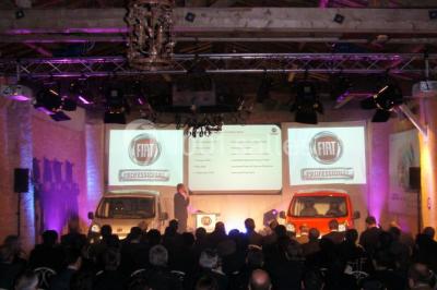 Cour d'une maison en pierre avec façade recouverte de lierre, arbres en arrière-plan et ciel bleu dégagé.