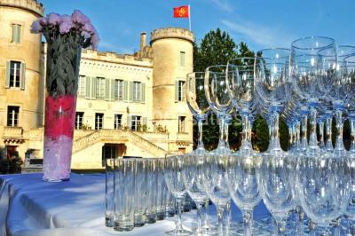 Cour d'une maison en pierre avec façade recouverte de lierre, arbres en arrière-plan et ciel bleu dégagé.