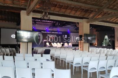 Cour d'une maison en pierre avec façade recouverte de lierre, arbres en arrière-plan et ciel bleu dégagé.