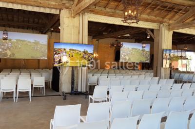 Cour d'une maison en pierre avec façade recouverte de lierre, arbres en arrière-plan et ciel bleu dégagé.