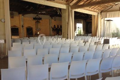 Cour d'une maison en pierre avec façade recouverte de lierre, arbres en arrière-plan et ciel bleu dégagé.