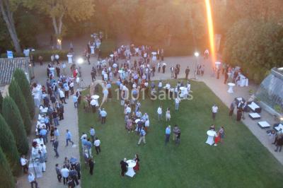 Cour d'une maison en pierre avec façade recouverte de lierre, arbres en arrière-plan et ciel bleu dégagé.