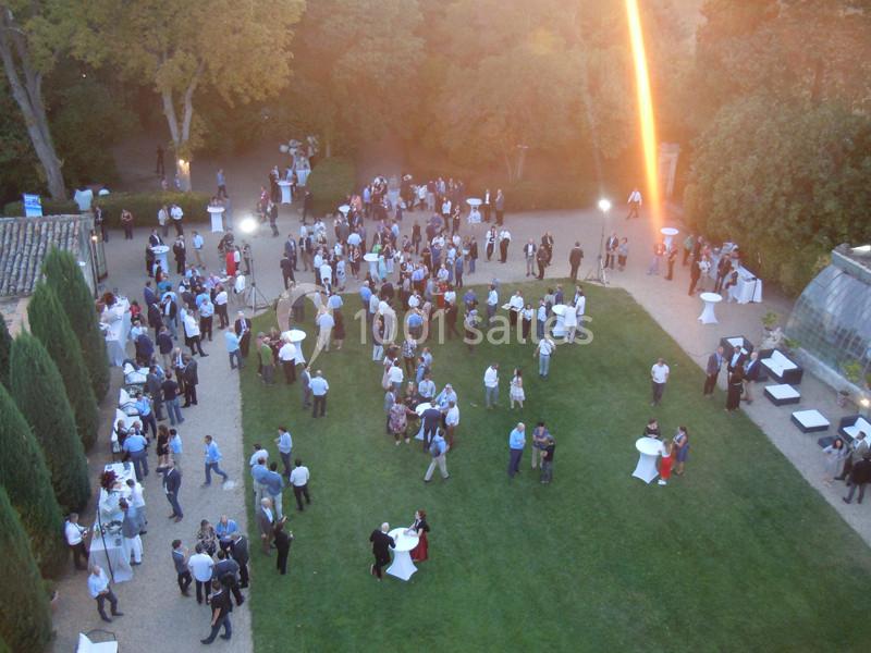 Vue aérienne d'un événement en plein air avec des groupes de personnes discutant dans un jardin au coucher du soleil.
