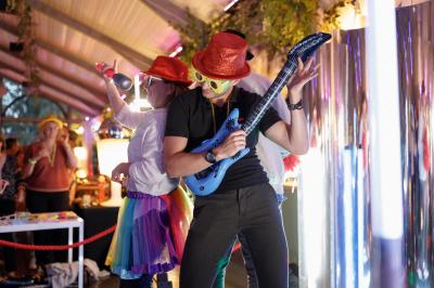 Deux personnes déguisées dansent et miment de jouer de la musique lors d'une fête dans un espace décoré.