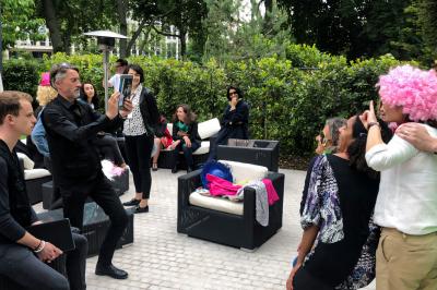 Des personnes debout en cercle dans une grande salle colorée, participant à une activité collective.