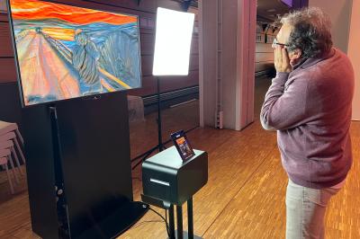 Des personnes debout en cercle dans une grande salle colorée, participant à une activité collective.