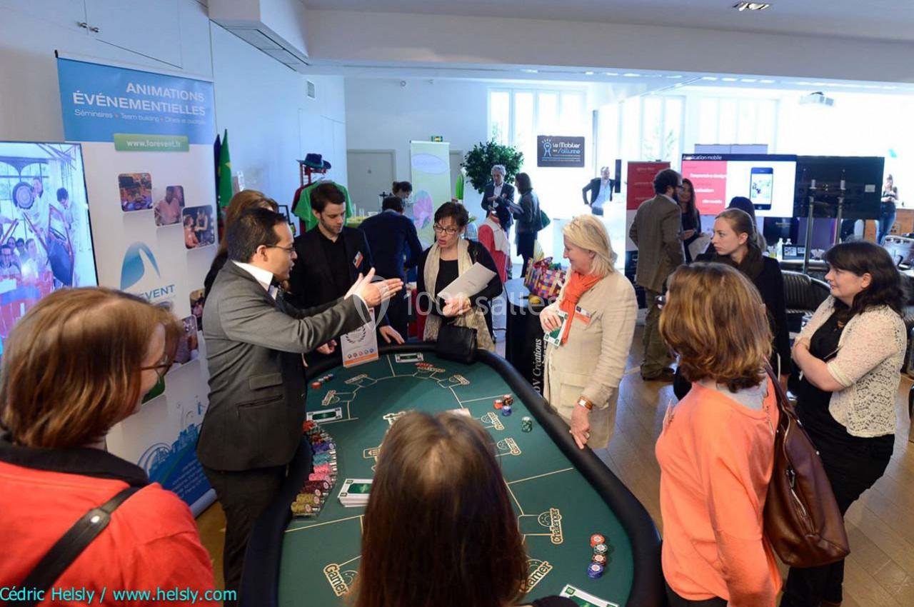 Un groupe de personnes autour d'une table de casino lors d'une présentation dans un espace événementiel lumineux.