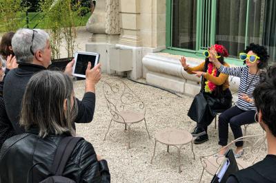Des personnes debout en cercle dans une grande salle colorée, participant à une activité collective.