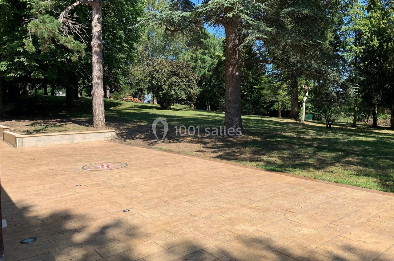 Location salle Monceaux (Oise) - Domaine de Monceaux #11 Terrasse en bois clair donnant sur un parc arboré avec pelouse et arbres sous un ciel dégagé.
