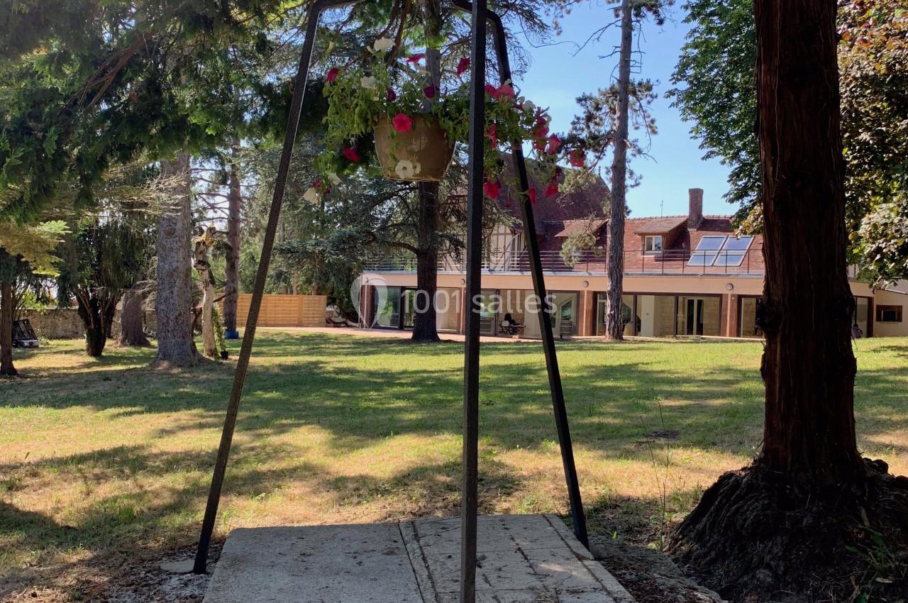Location salle Monceaux (Oise) - Domaine de Monceaux #13 Un puits en pierre surmonté d'une structure métallique avec un pot de fleurs, entouré d'arbres dans un jardin.