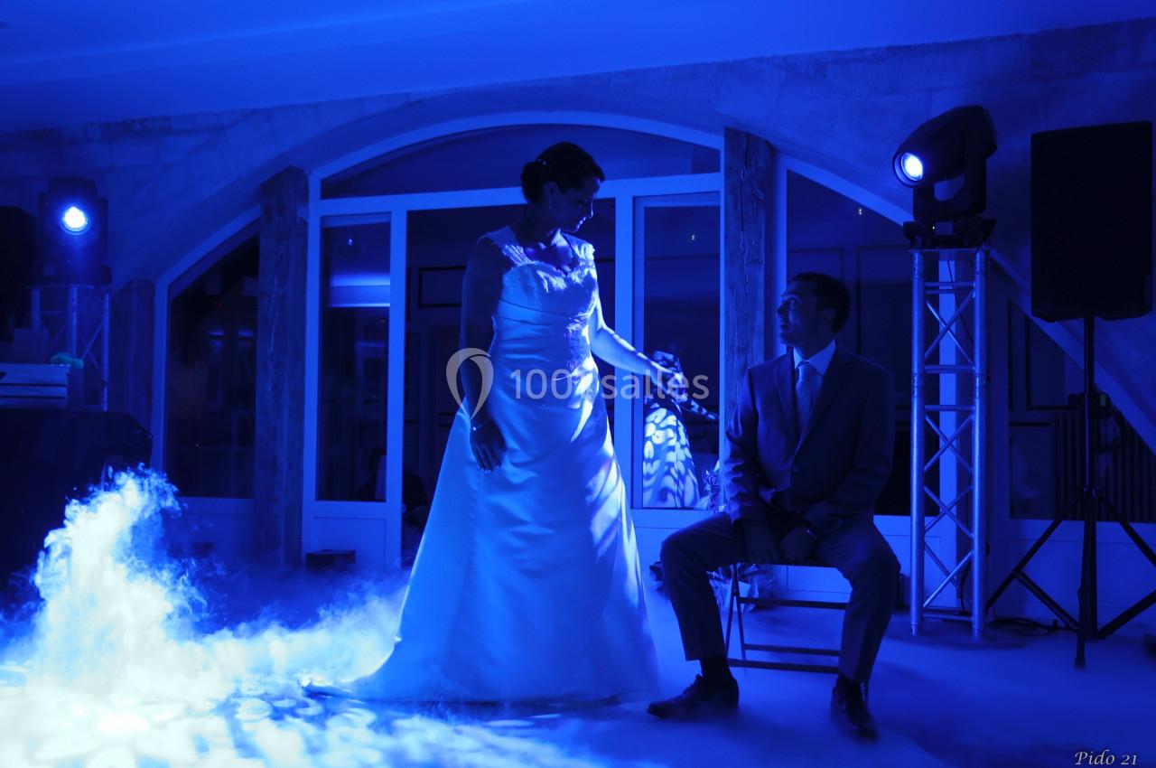 Location salle Monceaux (Oise) - Domaine de Monceaux #2 Une mariée en robe blanche et un homme en costume assis, éclairés par une lumière bleue dans une ambiance festive.