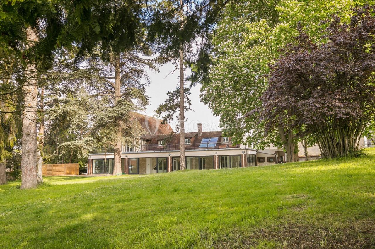 Location salle Monceaux (Oise) - Domaine de Monceaux #3 Grande maison entourée d'arbres et d'une pelouse verdoyante, vue depuis un jardin spacieux.
