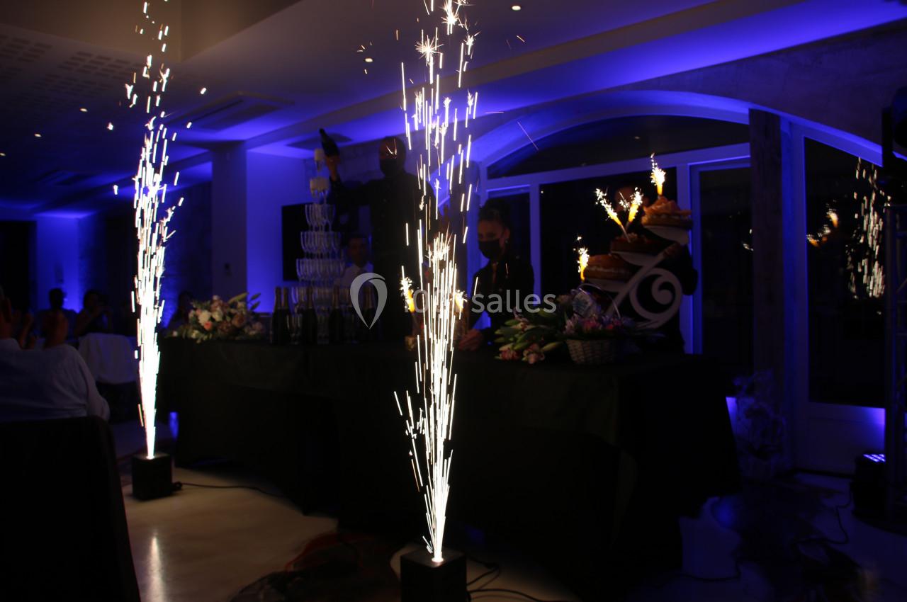 Location salle Monceaux (Oise) - Domaine de Monceaux #9 Effets pyrotechniques illuminant une salle sombre lors d'une célébration, avec des décorations et des desserts en arrière…