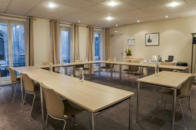 Façade d'un immeuble en pierre avec des fenêtres vitrées et un parterre de fleurs en bordure de trottoir.