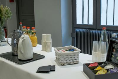 Façade d'un immeuble en pierre avec des fenêtres vitrées et un parterre de fleurs en bordure de trottoir.