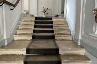 Façade d'un immeuble en pierre avec des fenêtres vitrées et un parterre de fleurs en bordure de trottoir.