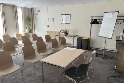 Façade d'un immeuble en pierre avec des fenêtres vitrées et un parterre de fleurs en bordure de trottoir.
