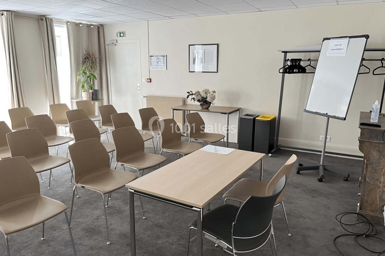 Salle de réunion lumineuse avec des chaises alignées, une table, un tableau blanc et un portant à vêtements.