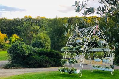 Arrangements floraux sur des supports en bois disposés sur une table recouverte d'une nappe blanche devant un mur en pierre.