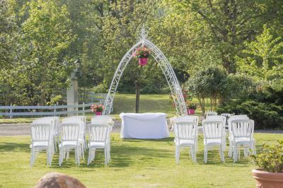 Arrangements floraux sur des supports en bois disposés sur une table recouverte d'une nappe blanche devant un mur en pierre.