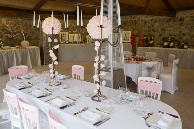 Arrangements floraux sur des supports en bois disposés sur une table recouverte d'une nappe blanche devant un mur en pierre.
