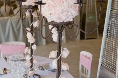 Arrangements floraux sur des supports en bois disposés sur une table recouverte d'une nappe blanche devant un mur en pierre.