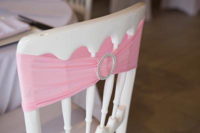 Arrangements floraux sur des supports en bois disposés sur une table recouverte d'une nappe blanche devant un mur en pierre.