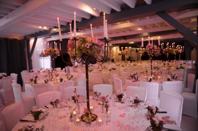 Arrangements floraux sur des supports en bois disposés sur une table recouverte d'une nappe blanche devant un mur en pierre.