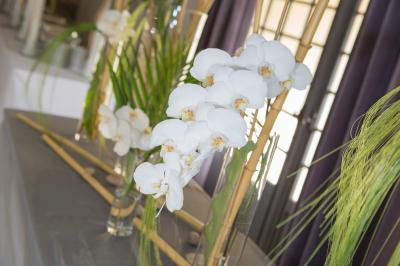 Arrangements floraux sur des supports en bois disposés sur une table recouverte d'une nappe blanche devant un mur en pierre.