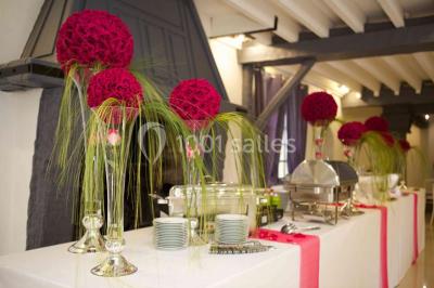 Arrangements floraux sur des supports en bois disposés sur une table recouverte d'une nappe blanche devant un mur en pierre.