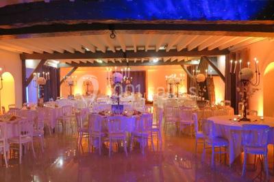 Arrangements floraux sur des supports en bois disposés sur une table recouverte d'une nappe blanche devant un mur en pierre.