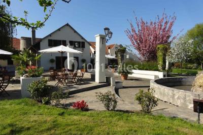 Arrangements floraux sur des supports en bois disposés sur une table recouverte d'une nappe blanche devant un mur en pierre.