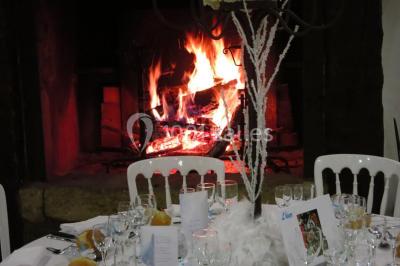 Arrangements floraux sur des supports en bois disposés sur une table recouverte d'une nappe blanche devant un mur en pierre.