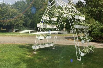 Arrangements floraux sur des supports en bois disposés sur une table recouverte d'une nappe blanche devant un mur en pierre.
