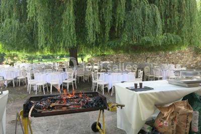 Arrangements floraux sur des supports en bois disposés sur une table recouverte d'une nappe blanche devant un mur en pierre.