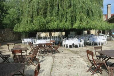 Arrangements floraux sur des supports en bois disposés sur une table recouverte d'une nappe blanche devant un mur en pierre.