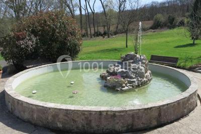 Arrangements floraux sur des supports en bois disposés sur une table recouverte d'une nappe blanche devant un mur en pierre.