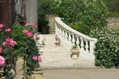 Arrangements floraux sur des supports en bois disposés sur une table recouverte d'une nappe blanche devant un mur en pierre.